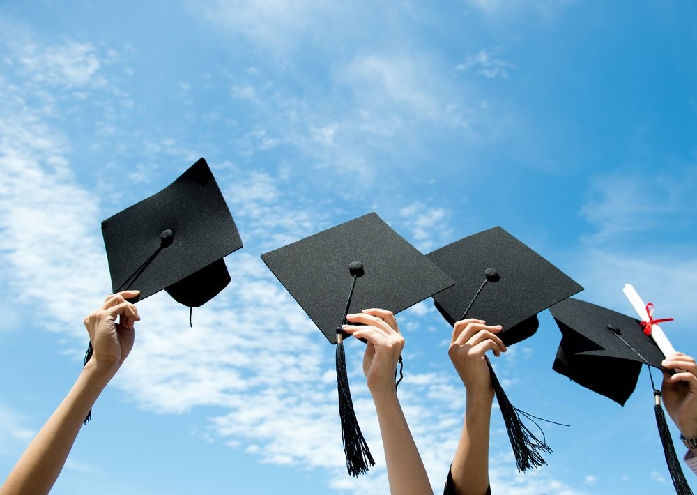 An image of student's holding up their graduation caps after graduating
